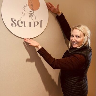 woman pointing to logo for Sculpt hanging on wall